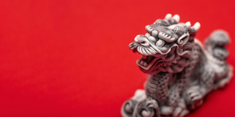 Gray dragon statue on a red background. The symbol of 2024. Happy Chinese New Year.