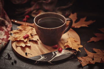Cozy scene for cold weather with cup of coffee and dried leaves. Autumn composition with hot drink and foliage. Autumnal mood, slow living concept