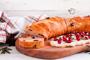 Cranberry baguette with pomegranate cream cheese spread. Table scene against a white wood background. Winter or Christmas theme appetizer.