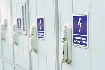 On a metal cabinet with electrical equipment there is a blue sign with a lightning bolt and an...