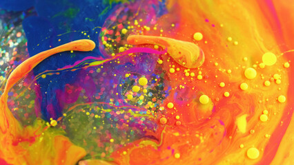 Abstract colorful background. Sequins paint. Fluid art. Mixed vivid yellow red blue green liquid oil bubbles spinning on water surface with round glitter.