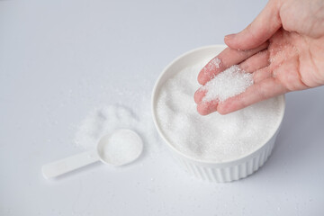 Epsom salt in hand for bath on white background. Useful salt for relaxation in the bath. Magnesium salt