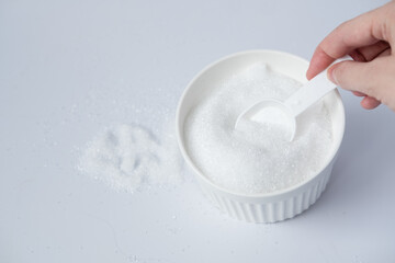 Epsom salts in a bath measuring spoon on a white background. Useful salt for relaxation in the bath. Magnesium salt