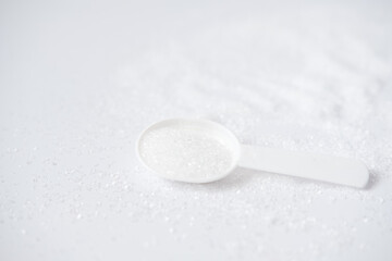 Epsom salts in a bath measuring spoon on a white background. Useful salt for relaxation in the bath. Magnesium salt