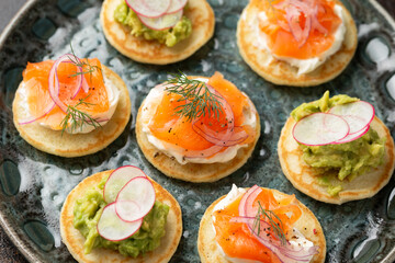Mini blini pancakes with soft cheese, cold smoked salmon and guacamole - obrazy, fototapety, plakaty