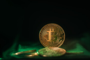 Bitcoin gold coin close-up. BTC with green backlight on a black background.