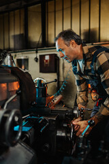 Portrait frame of a machinist operating a lathe machine in a factory.