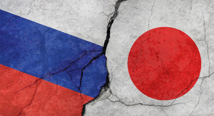 Russia and Japan flags, concrete wall texture with cracks, grunge background, military conflict concept