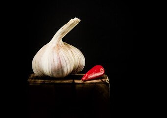 Head of garlic with red pepper on a dark background.