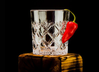 Red hot pepper on a crystal glass dark background.