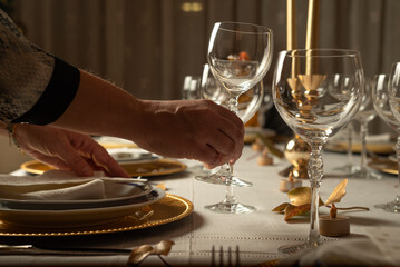 Unrecognizable  woman organizing elegant Christmas meal. Close up photo of female hands setting the table for Christmas meal at home. - obrazy, fototapety, plakaty