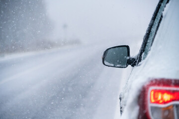 The car is driving on a winter road in a blizzard.