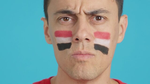 Serious man with a egyptian flag painted on the face