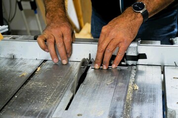 Hände von Mann an Sägemaschine in Werkstatt