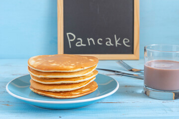 Pancakes in ceramic plate for tasty breakfast on wooden background.