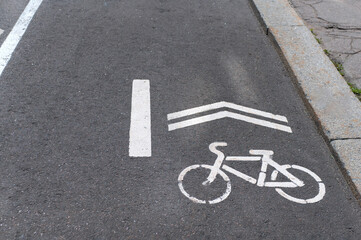 the designation of the bike path on the asphalt. Bicycle sign and the direction of application of white paint on asphalt