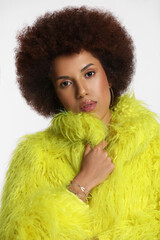 Portrait of beautiful young woman in stylish yellow fur coat on white background