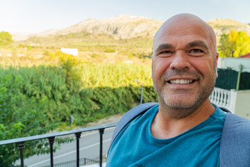 Happy man takes a selfie outdoors, landscape on background. 