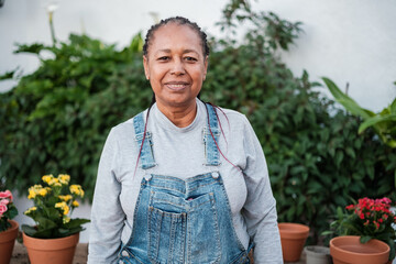 Senior woman in denim overalls gardening outdoors in her garden. Concept: lifestyle, gardening, botany.