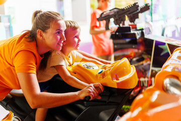 Mother and son play in an arcade motorcycle simulator in an entertainment center