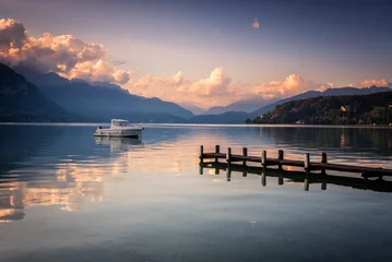 Muurstickers Boat next to a dock in the calm waters of Lake Annecy and the Alps mountain range in the background at sunset, Lake Annecy, Auvergne - Rhône - Alps, France, Europe © JMDuran Photography
