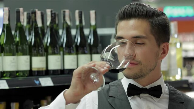 Image of confident male sommelier examining wine
