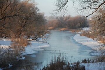 Frozen river and trees on the bank. winter landscape on a frosty day.