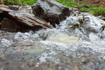 Raging water of a fast mountain river in a picturesque beautiful mountainous area, flowing water with splashes, selective focus