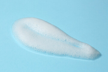 Foam on light blue background. Face cleanser, skin care cosmetic