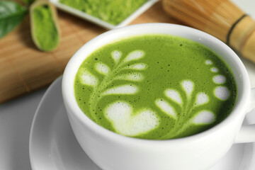 Delicious matcha latte in cup on white table, closeup