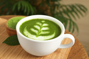 Delicious matcha latte in cup and powder on wooden coffee table, closeup