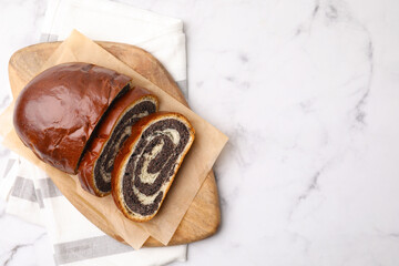 Cut poppy seed roll on white marble table, top view with space for text. Tasty cake