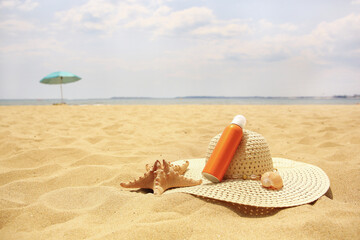 Sunscreen, hat and starfish on sand, space for text. Sun protection care