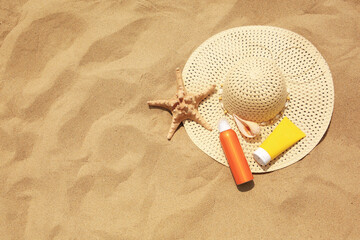 Flat lay composition with sunscreens on sand, space for text. Sun protection care