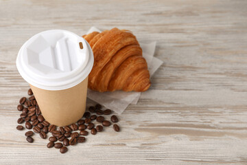 Coffee to go. Paper cup with tasty drink, croissant and beans on white wooden table. Space for text