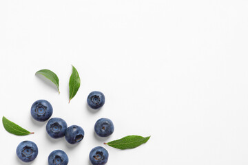 Tasty fresh blueberries with green leaves on white background, flat lay. Space for text