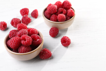 Tasty ripe raspberries on white wooden table, space for text