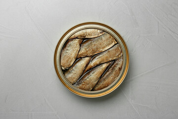 Open tin can of sprats on light grey table, top view