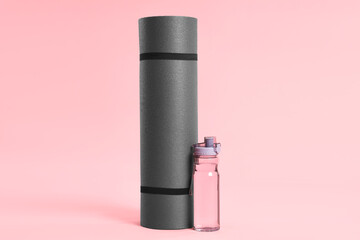 Obraz premium Grey yoga mat and bottle of water on pink background