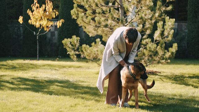 mom with her son in the garden with there dog sitting and playing near the trees