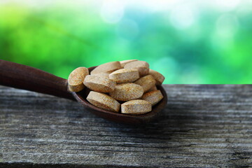 Herbal ayurvedic tablet or pills in wooden spoon isolated