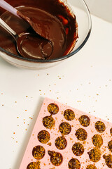 There is a silicone mold filled with chocolate mixture on the table. Making chocolates.