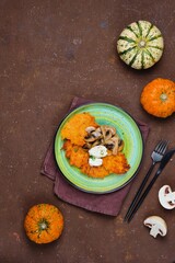 Pumpkin fritters with mushrooms and cream cheese on a green plate on a brown concrete background. Pumpkin recipes.