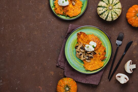 Pumpkin fritters with mushrooms and cream cheese on a green plate on a brown concrete background. Pumpkin recipes.