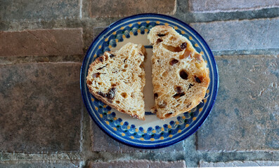 Two slices of Panettone Italian fruitcake or sweetbread on a decorative blue and yellow dessert plate
