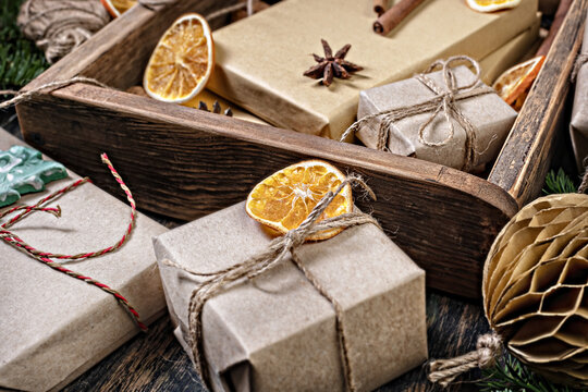 Wrapping rustic eco Christmas packages with brown paper and string on dark background