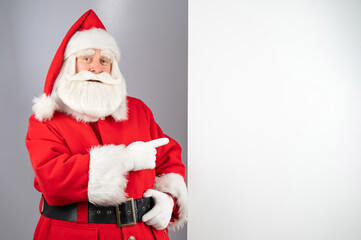Santa claus points to an empty space. Christmas advertisement.