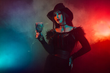 Stunning gorgeous lady witch prepare hot powerful love potion ritual on halloween night over neon mist background