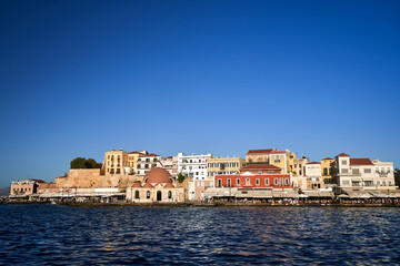 Fototapeta na wymiar Taverns, historic buildings and crowds of tourists in the port of Chania on the island of Crete