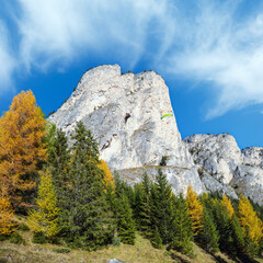 Autumn alpine Dolomites mountain scene and unrecognizable paragliders in sky. Peaceful view near Wolkenstein in Groden, Selva di Val Gardena, Sudtirol, Italy.